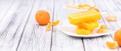 Homemade Tangerine Popsicles with some fresh fruits (close-up shot) on a vintage background