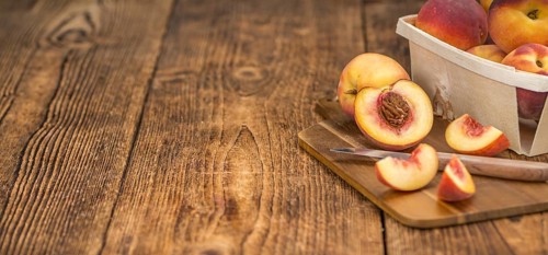 Fresh Peaches as high detailed close-up shot on a vintage wooden table, selective focus