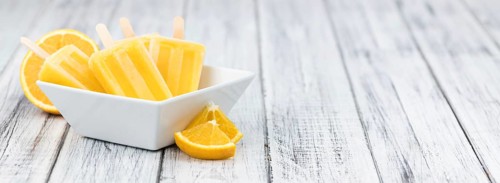 Some homemade orange popsicles (selective focus) on a vintage background
