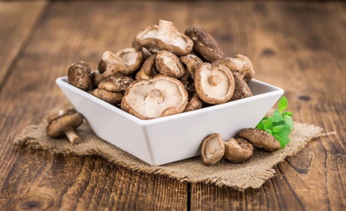 Shiitake mushrooms on an old wooden table as detailed close-up shot, selective focus