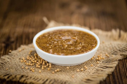 Mustard (sweet) on rustic wooden background (close-up shot)