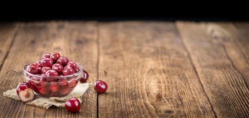 Canned Cherries as high detailed close-up shot on a vintage wooden table, selective focus