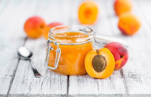 Apricot Jam on an old wooden table as detailed close-up shot (selective focus)