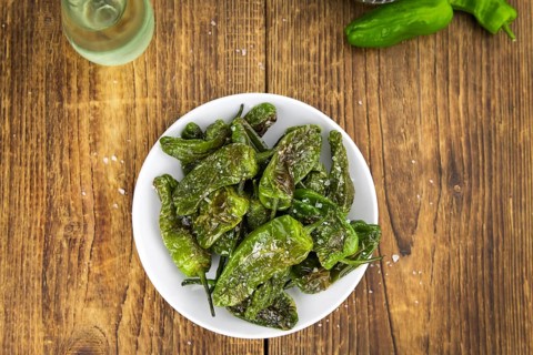 Pimientos de Padron on an old wooden table as detailed close-up shot, selective focus
