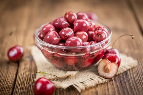 Canned Cherries as high detailed close-up shot on a vintage wooden table, selective focus