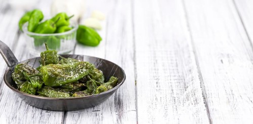 Pimientos de Padron on rustic wooden background as close-up shot