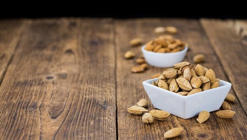 Roasted and salted Almonds (with shell) on a vintage background (close-up shot)