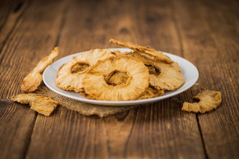 Pineapple rings (dried) on an old wooden table as detailed close-up shot, selective focus
