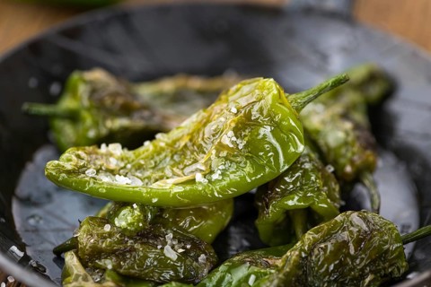 Pimientos de Padron on rustic wooden background as close-up shot