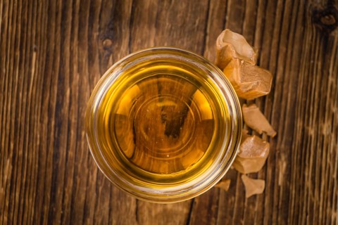 Caramel Syrup as high detailed close-up shot on a vintage wooden table (selective focus)