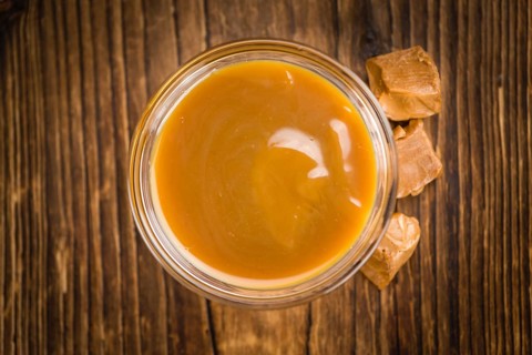 Caramel Sauce on an old wooden table as detailed close-up shot (selective focus)
