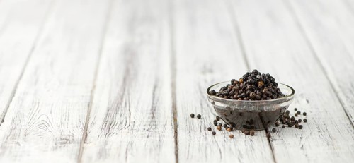 Preserved black Peppercorns on wooden background, selective focus, close-up shot