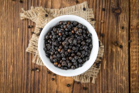 Preserved black Peppercorns on wooden background, selective focus, close-up shot