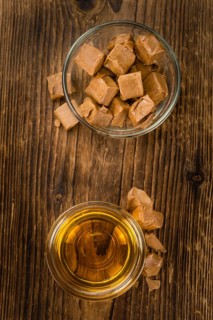 Syrup (Caramel taste) on an old wooden table as detailed close-up shot (selective focus)