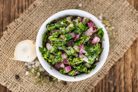 Healthy homemade Chimichurri on a wooden table as detailed close-up shot (selective focus)