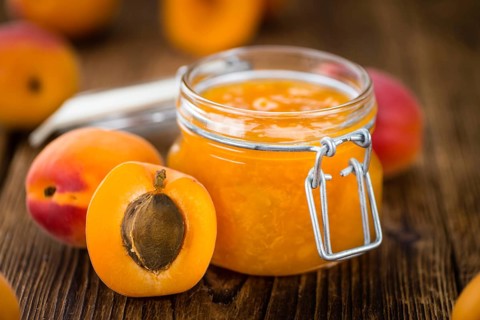 Apricot Jam on an old wooden table as detailed close-up shot (selective focus)