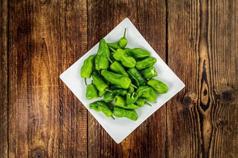 Raw Pimientos on an old wooden table as detailed close-up shot, selective focus