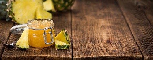 Pineapple Jam as high detailed close-up shot on a vintage wooden table, selective focus