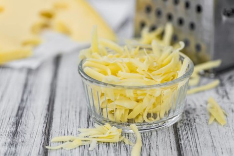 Old wooden table with grated Cheese (close-up shot)