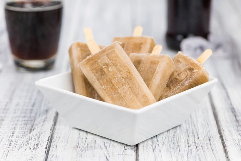 Fresh made Cola Popsicles on wooden background (selective focus, close-up shot)