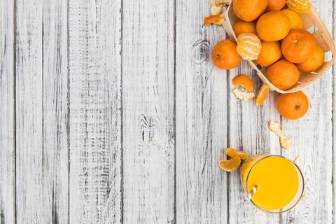 Wooden table with fresh homemade Tangerine Juice (close-up shot, selective focus)