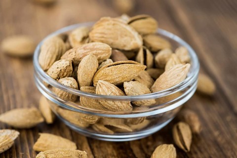 Roasted Almonds (in shell) on an old wooden table (close-up shot, selective focus)