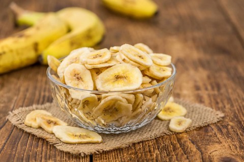 Homemade Dried Banana Chips on an wooden table as detailed close-up shot, selective focus