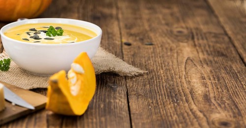 Portion of fresh made Pumpkin Soup (close-up shot) on rustic background