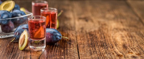 Homemade Plum Liqueur on an wooden table as detailed close-up shot, selective focus