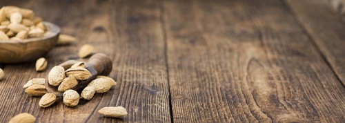 Roasted Almonds (in shell) on an old wooden table (close-up shot, selective focus)