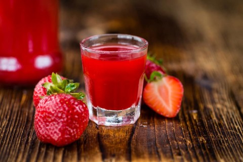 Homemade Strawberry liqueur on an wooden table as detailed close-up shot, selective focus