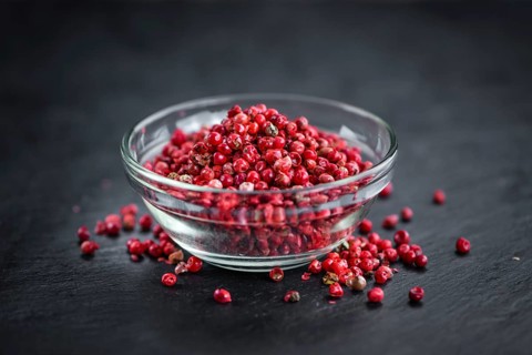 Portion of Pink Peppercorns on a rustic slate slab, selective focus, close-up shot