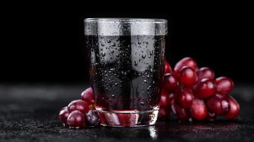Portion of healthy Red Grape Juice on a slate slab (selective focus)