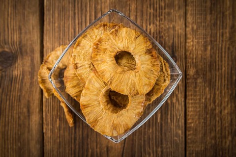Pineapple rings (dried) on rustic wooden background as close-up shot