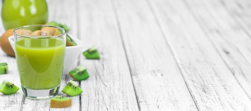 Wooden table with fresh made Kiwi Smoothie (close-up shot, selective focus)