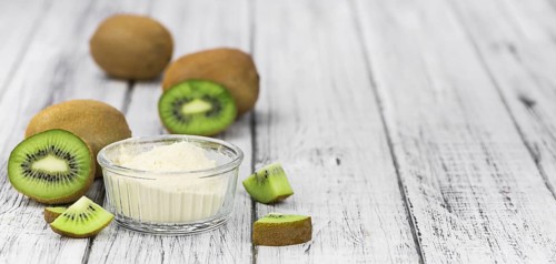 Bowl with fresh made Kiwi powder (close-up shot, selective focus) on an old wooden table