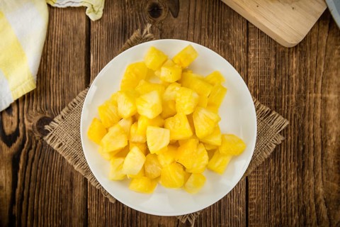 Sliced Pineapple on an old wooden table as detailed close-up shot, selective focus