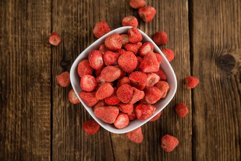 Strawberries (dried) as high detailed close-up shot on a vintage wooden table, selective focus