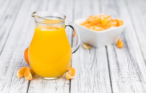 Wooden table with fresh homemade Tangerine Juice (close-up shot, selective focus)
