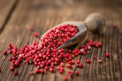 Pink Peppercorns on an old wooden table as detailed close-up shot, selective focus