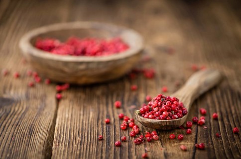 Pink Peppercorns as high detailed close-up shot on a vintage wooden table, selective focus
