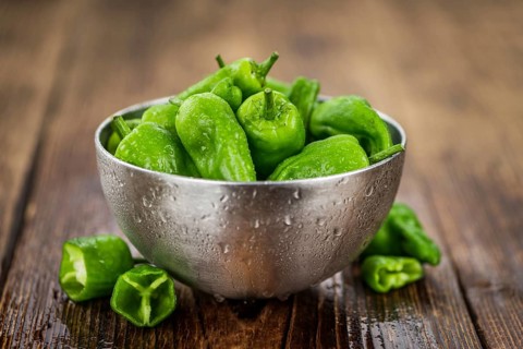 Raw Pimientos on an old wooden table as detailed close-up shot, selective focus