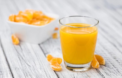 Homemade Tangerine Juice on an old and rustic wooden table (selective focus, close-up shot)