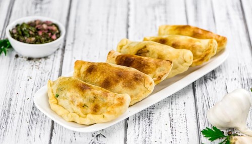 Wooden table with fresh homemade Empanadas (detailed close-up shot, selective focus)