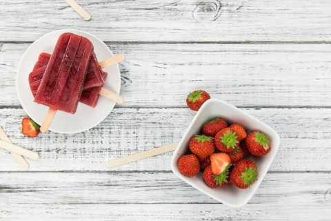 Homemade Strawberry Popsicles (close-up shot, selective focus) on vintage background