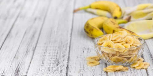 Homemade Dried Banana Chips on an wooden table as detailed close-up shot, selective focus