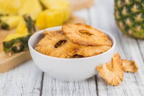 Pineapple rings (dried) on rustic wooden background as close-up shot