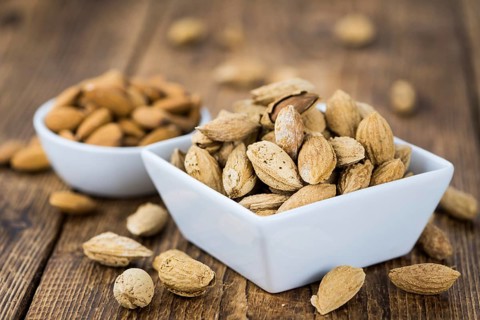 Roasted and salted Almonds (with shell) on a vintage background (close-up shot)