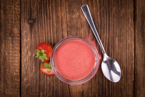 Strawberry powder as high detailed close-up shot on a vintage wooden table, selective focus