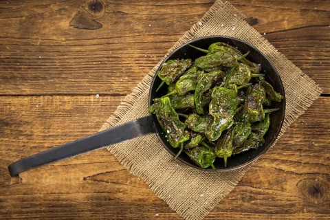 Pimientos de Padron on rustic wooden background as close-up shot